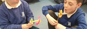 Two children in school uniform blowing on little windmills to make them spin