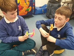 Two children in school uniform blowing on little windmills to make them spin