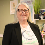 Our Founder Aine Wallace, wearing a blazer and a Fresh Minds Education in white with the word 'hope' visible, is smiling at the camera.