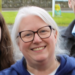 Founder Aine Wallace, smiling at the camera wearing glasses outside at an event