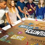 A workshop of young people around a colourful table with key words in various fonts